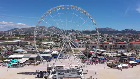 Big-wheel-amusement-park-Marseille-France-aerial-fix-shot-sunny-day-blue-sky